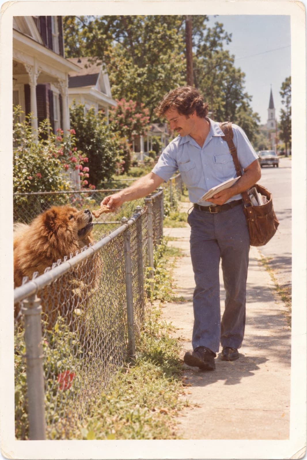Ray in his postal uniform offering a dog biscuit to a chow over a fence